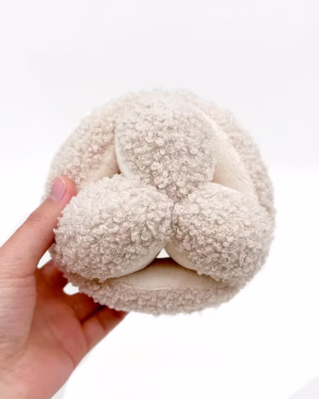 Hand holding SnuffleBall™ French Bulldog Chew Toy against white background